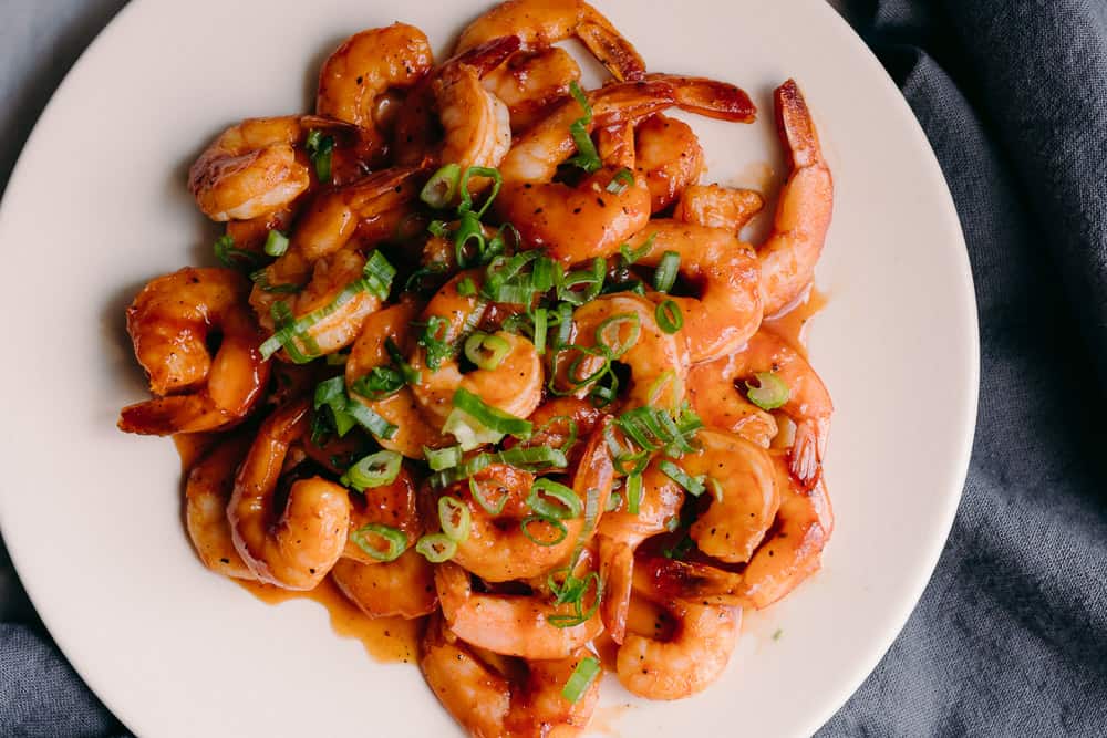 plate of beautiful shrimp with bbq sauce and green onions