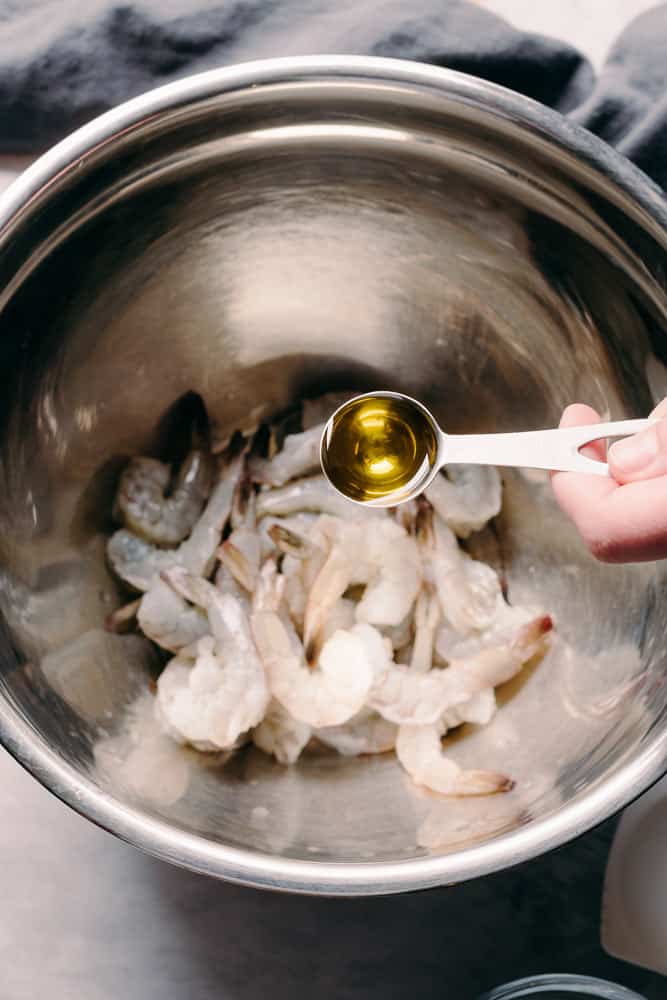 adding olive oil to raw shrimp