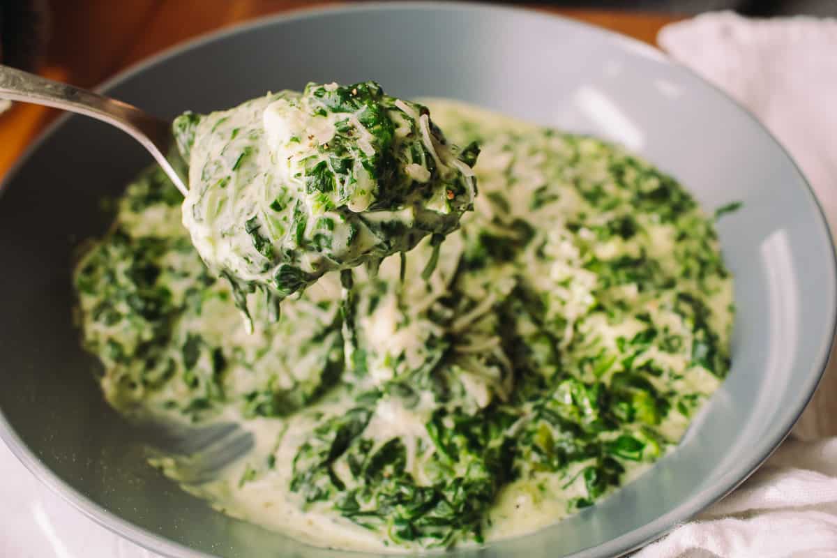 scooping creamed spinach out of a bowl