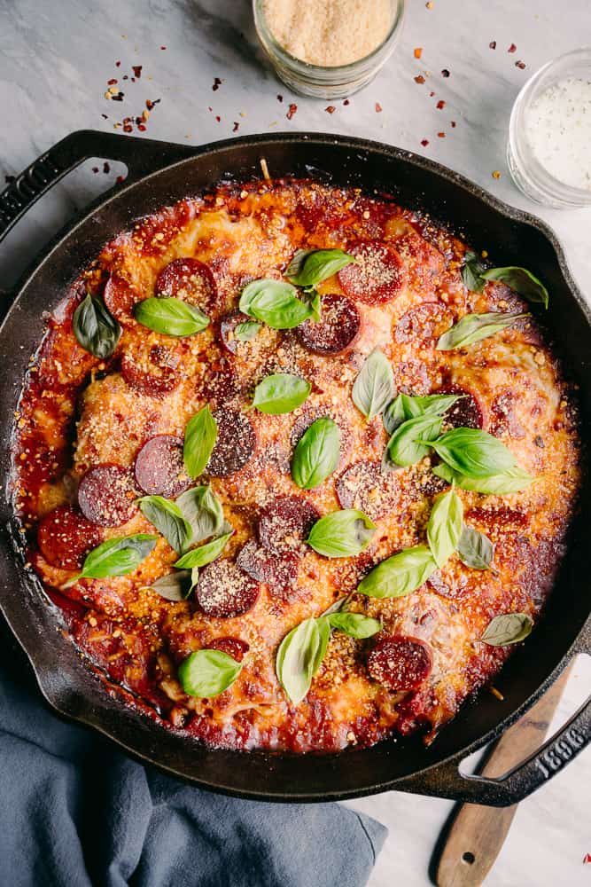 lodge cast iron skllet with baked pepperonis and cheese like a pizza with basil 