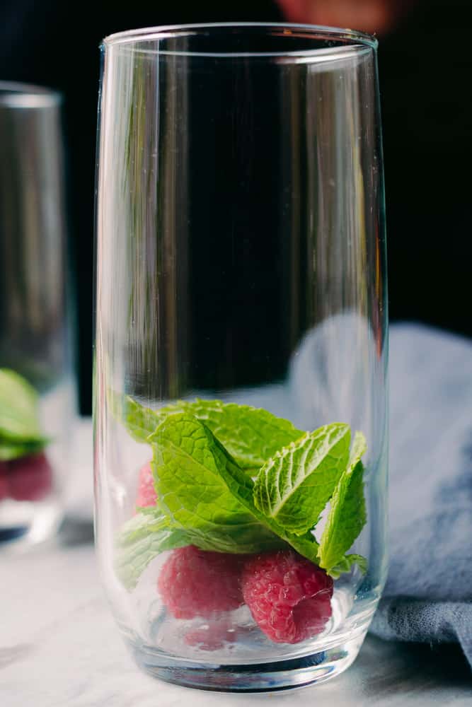 fresh mint leaves and raspberries in a tall glass
