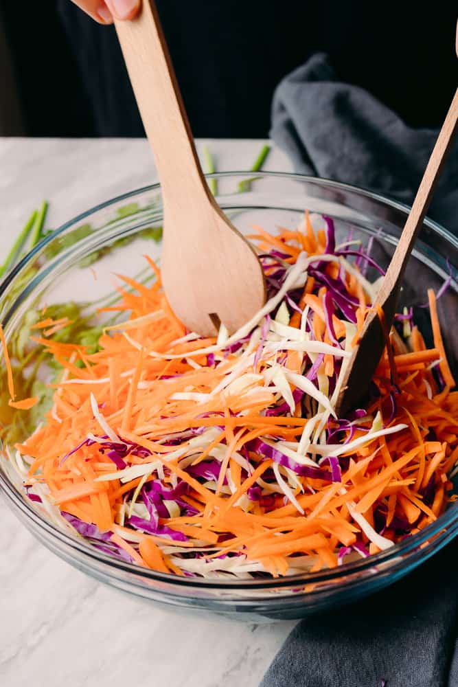 mixing carrots into cabbage salad