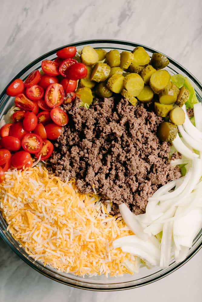 beef pickles cheese tomatoes onions in a bowl of salad