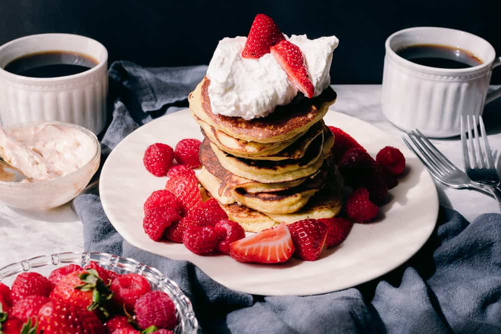 beautiful pancake stack with berries, coffee and whipped cream