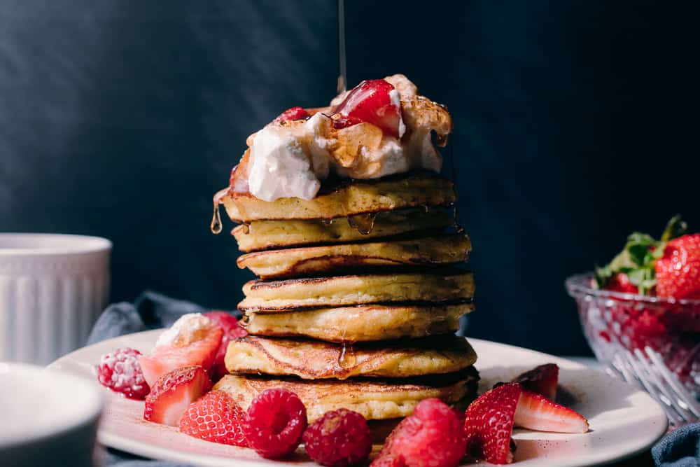 fluffy pancake stack with whipped cream berries and syrup