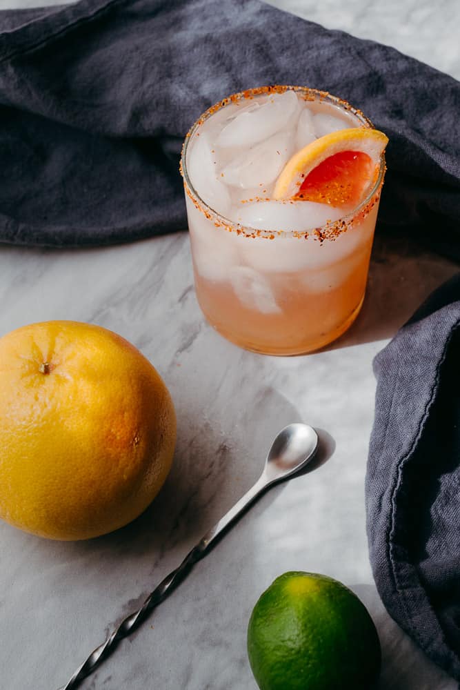 rosé paloma with bar spoon grapefruit and grey napkin with moody lighting