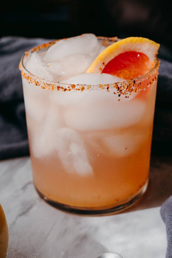 close up of a glass of a rosé paloma with fresh grapefruit and tajin rim