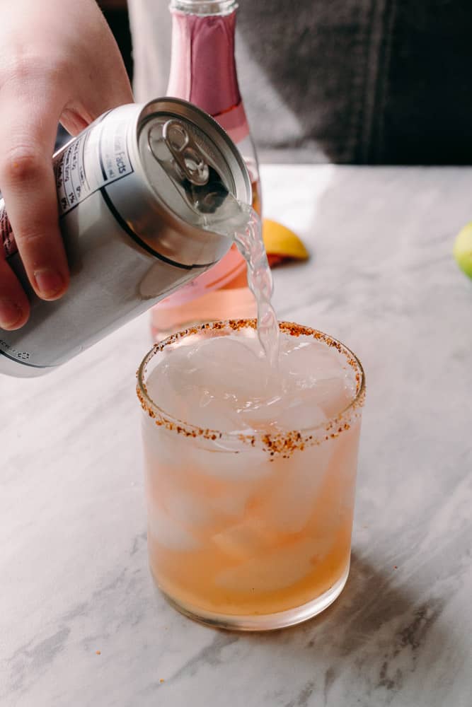 pouring ginger beer into a rosé ginger palomacocktail
