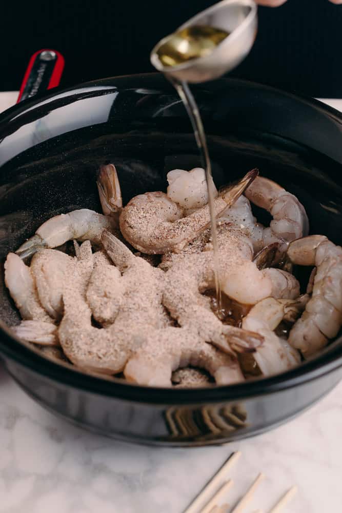 adding oil to shrimp with seasonings