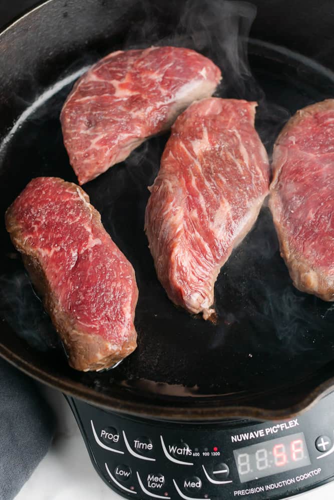 raw sirloin steaks in a cast iron skillet