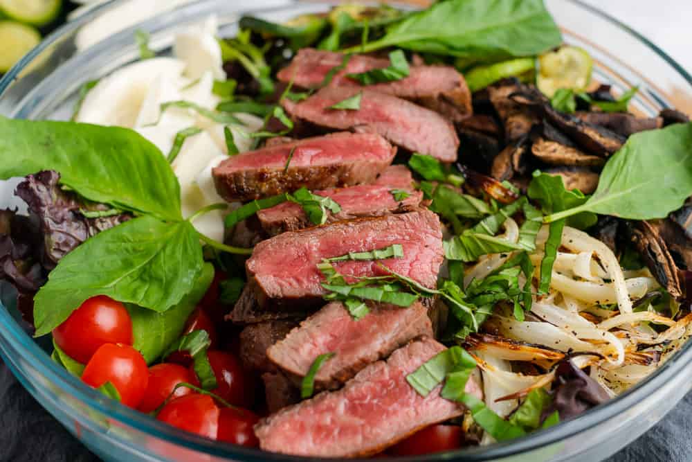 sirloin steak salad with medium rare steak and strips of basil