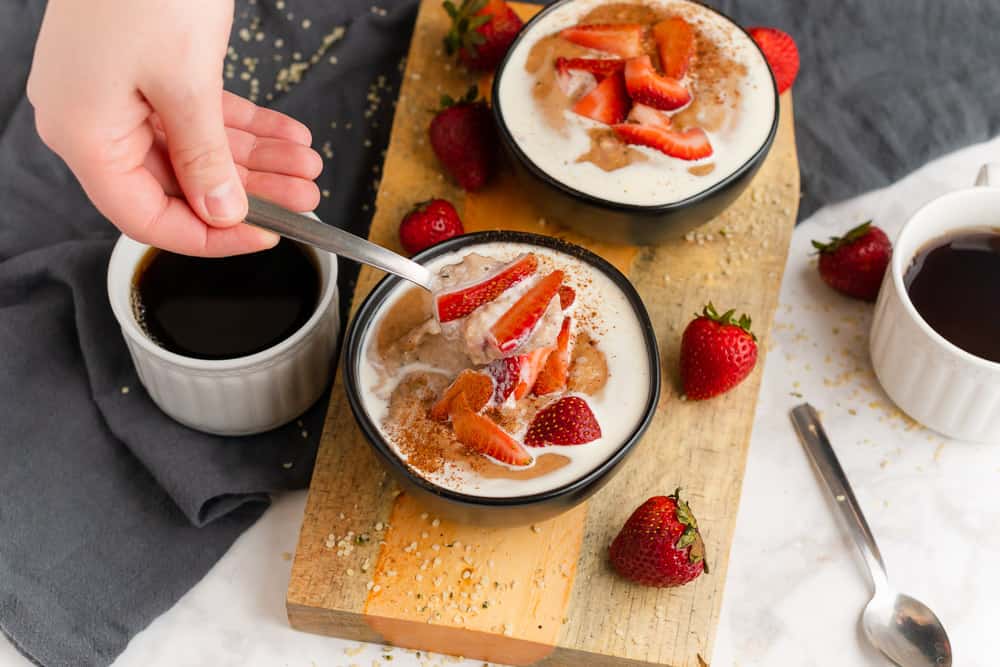 hand holding spoonful of hemp heart oatmeal with strawberries and cream