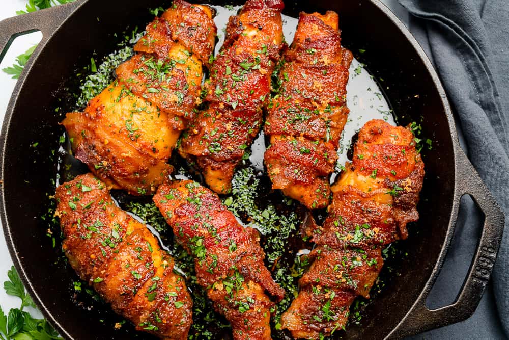 chicken wrapped with bacon in a cast iron skillet with parsley