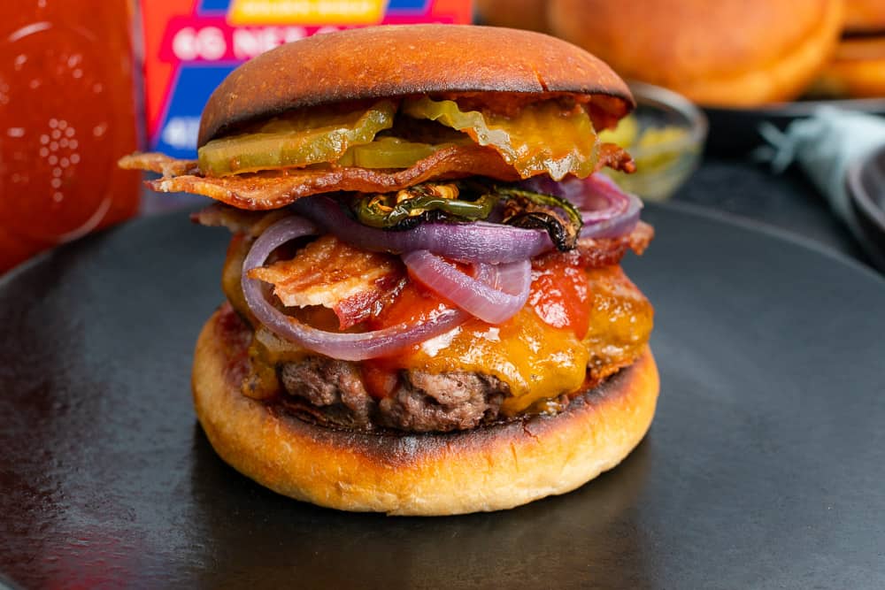 close up of Sola keto cheeseburger with red onions bbq sauce bacon and jalapenos