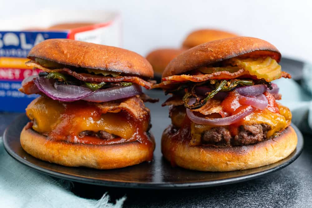 two bbq bacon cheeseburgers with red onion and jalapeños 