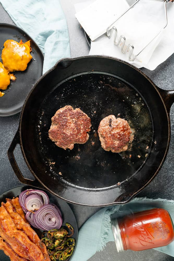 burger patties in a cast iron skillet with a caramelized crust