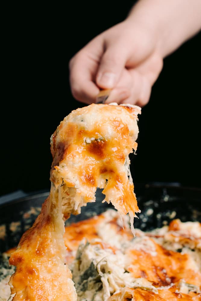 cheesy spinach artichoke dip in a cast iron skillet