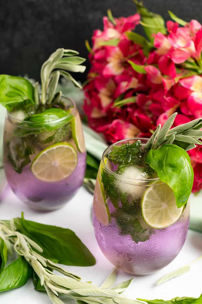 purple gin and tonic with basil sage and pink flowers 