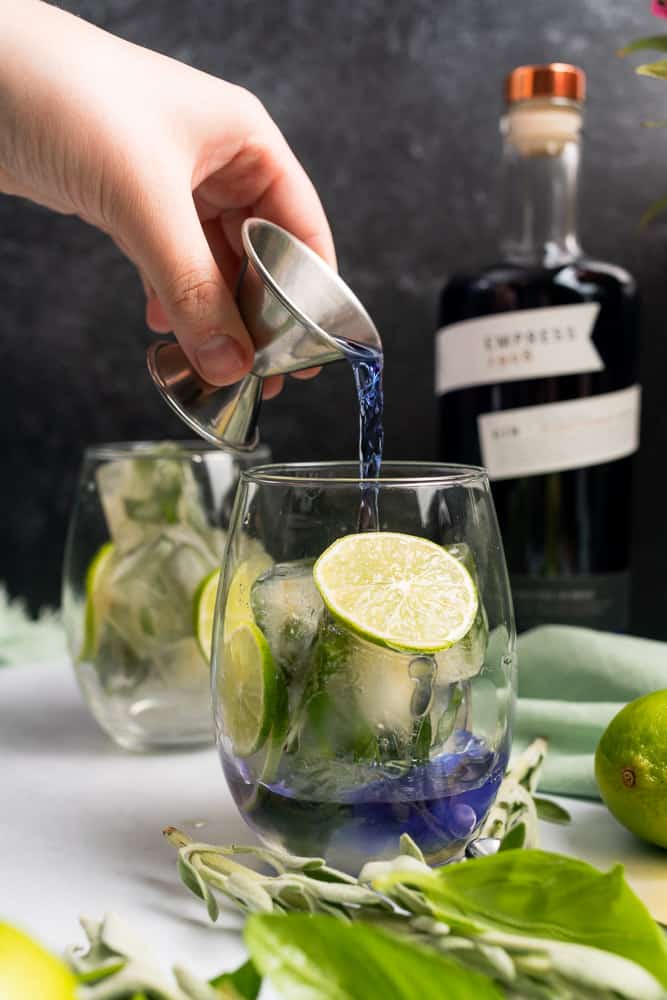 hand pouring empress gin into a summer herb gin and tonic ketococktail