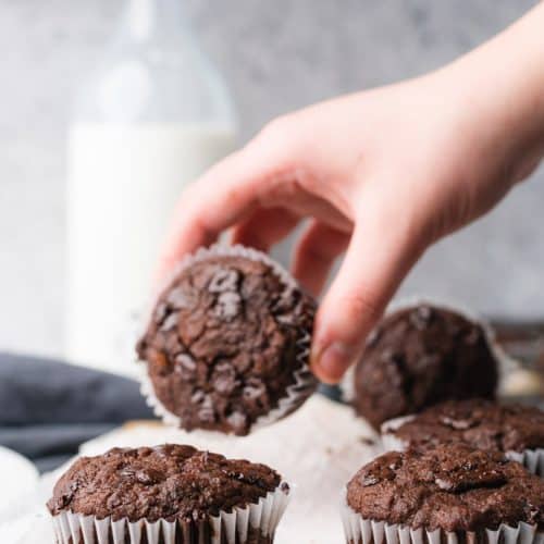 hand grabbing a chocolate muffin with milk bottle