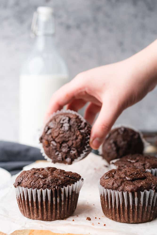 hand grabbing a chocolate muffin with milk bottle