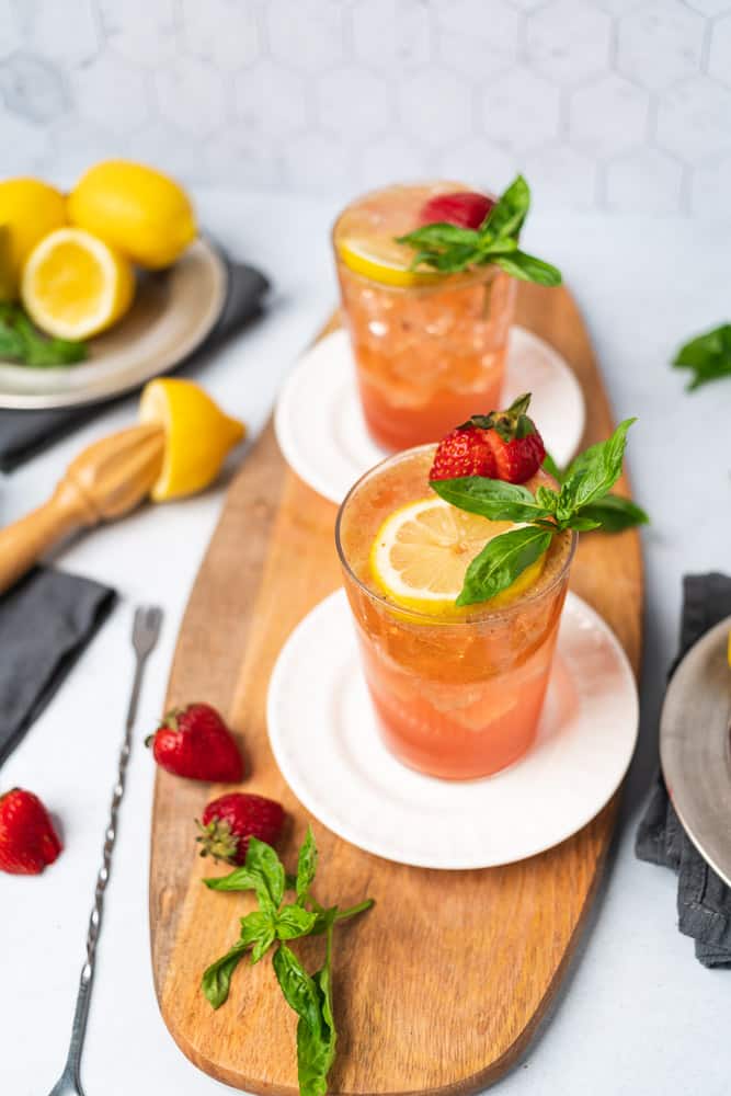 two glasses from a 45 degree angle of strawberry basil vodka lemonade cocktails with fresh ingredients