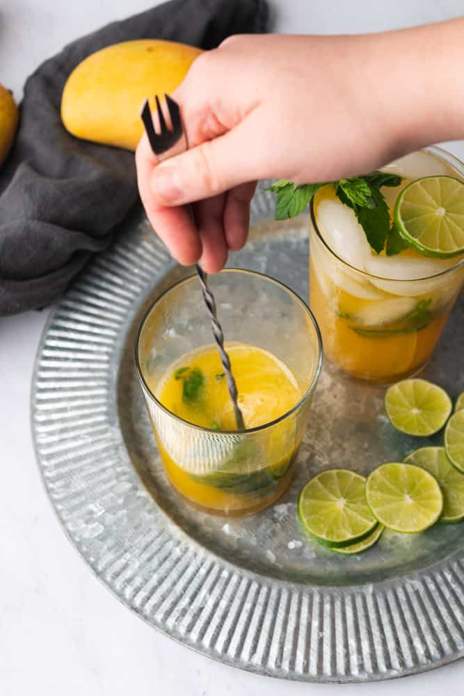 stirring the ingredients for a mango mojito