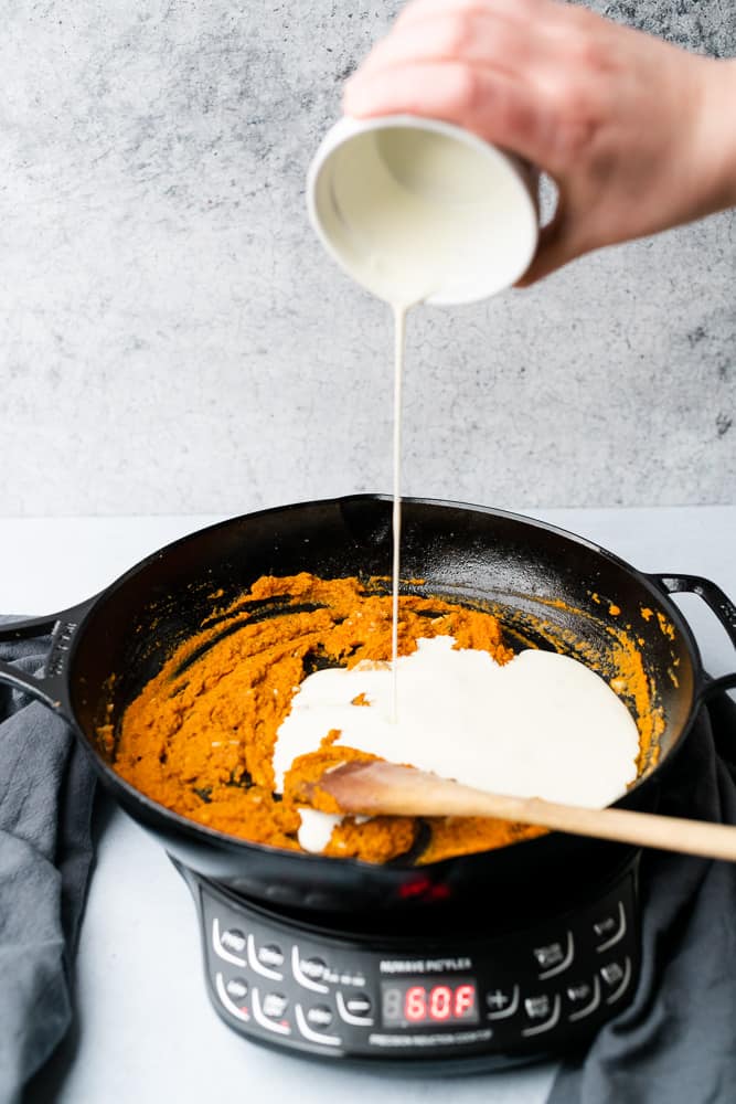adding cream to a pumpkin sauce