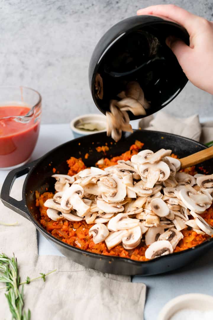 adding thinly sliced mushrooms to a pan