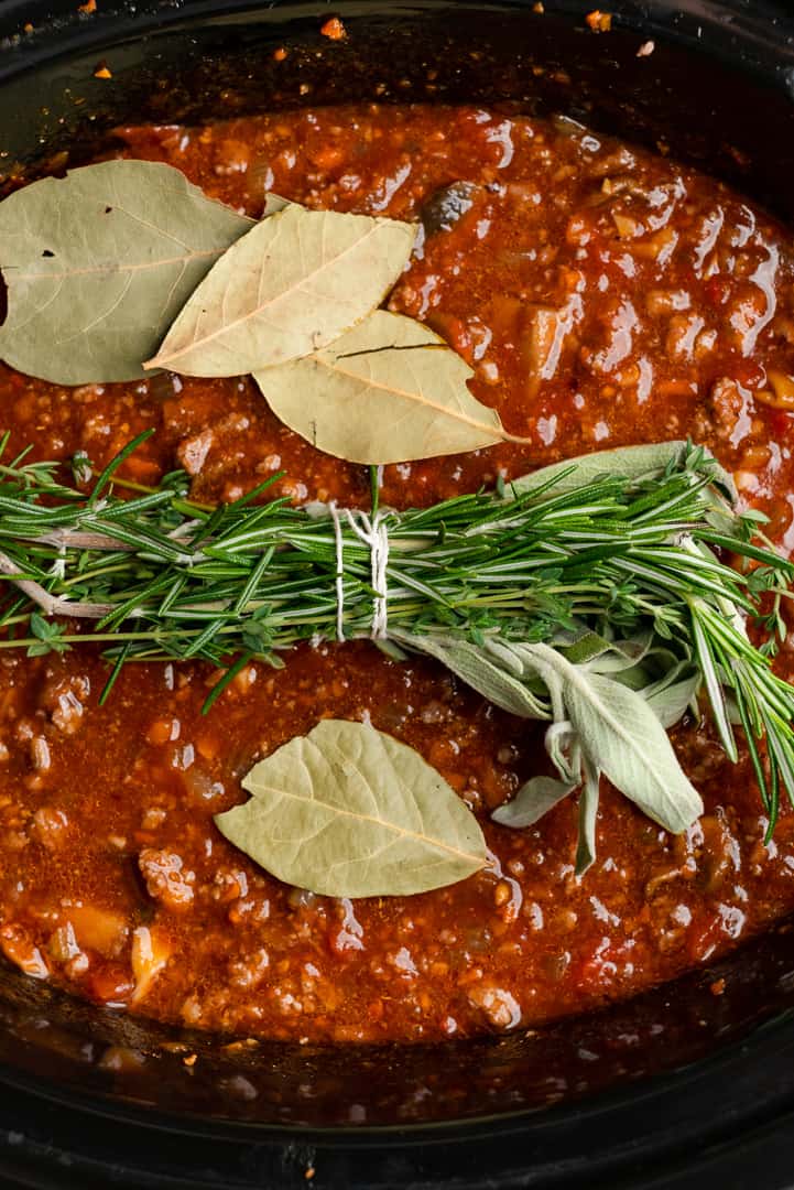 lamb pasta sauce with bundle of herbs and bay leaves