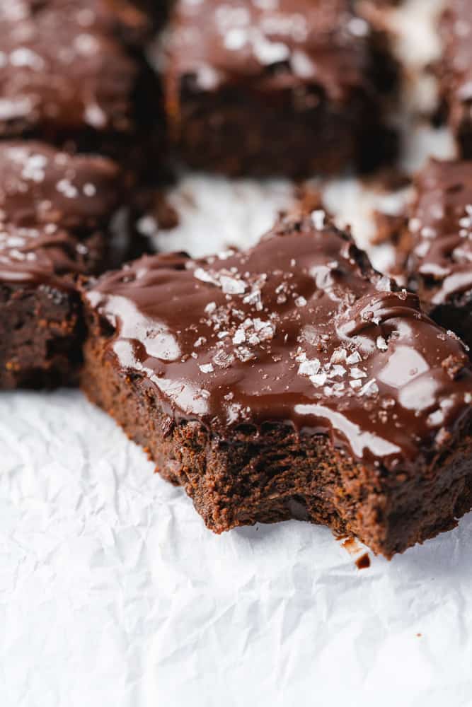 close up shot of pumpkin brownies topped with flaky sea salt with a bite taken out