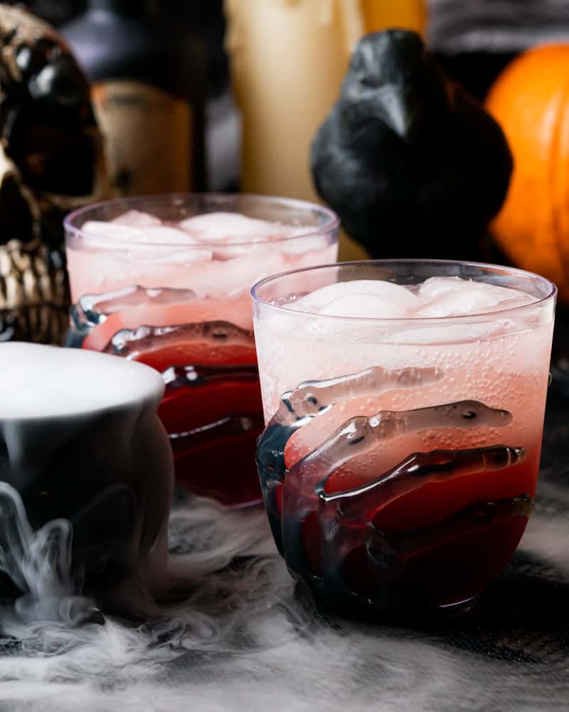 super spooky gin bennett next to a raven with skeleton glasses and dry ice in a cauldron