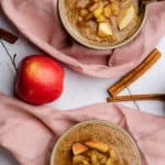 two bowls of apple spice hemp heart porridge with pink napkins and cinnamon sticks