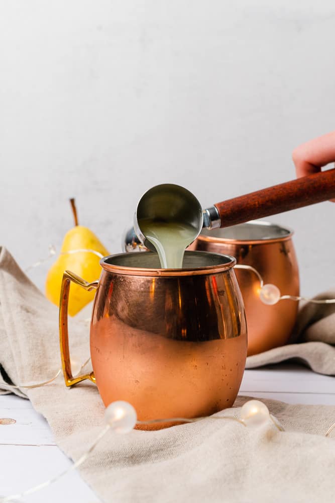 pouring lemon juice into a moscow mule mug