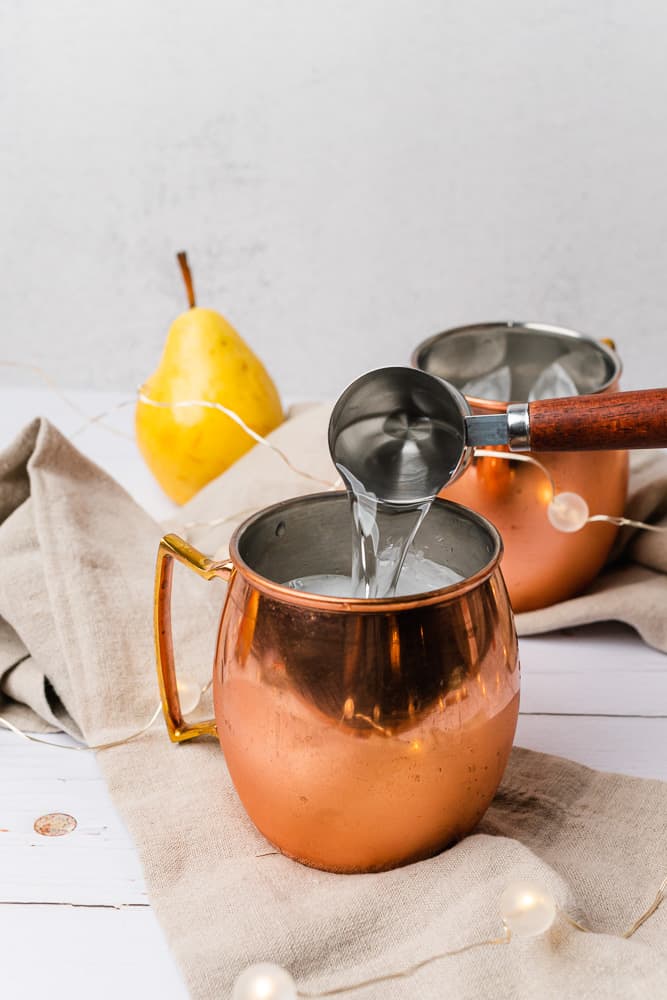 pouring vodka into a moscow mule mug