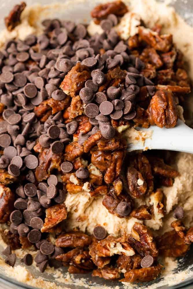 folding in chocolate chips and candied pecans into cookie dough