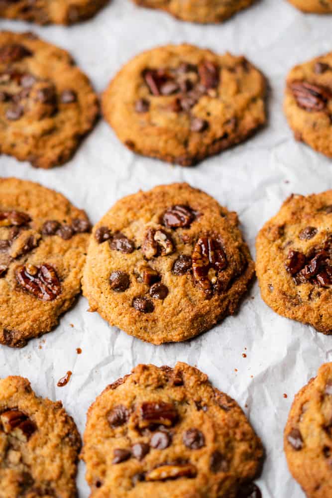 chocolate chip cookies with pecans on white parchment