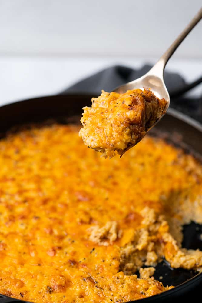 spoonful of cheesy cauliflower in a skillet