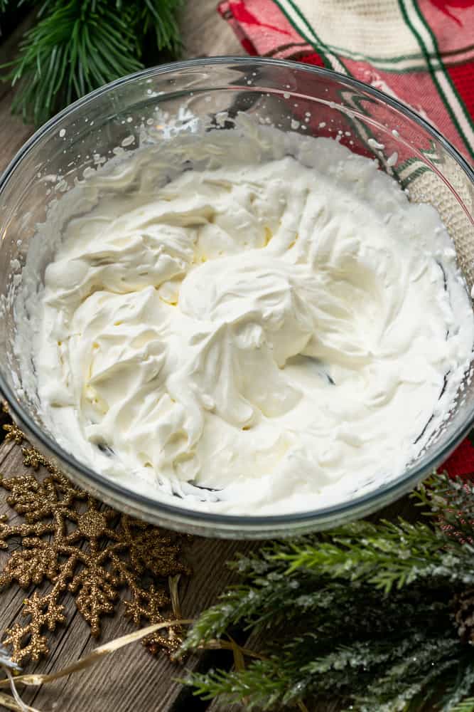 whipped cream in a bowl with christmas decorations surrounding it