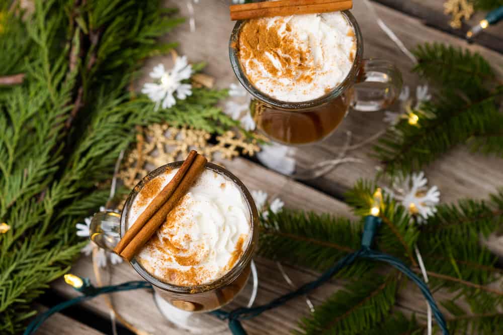 two irish coffee mugs with hot buttered rum, cinnamon, garland and lights