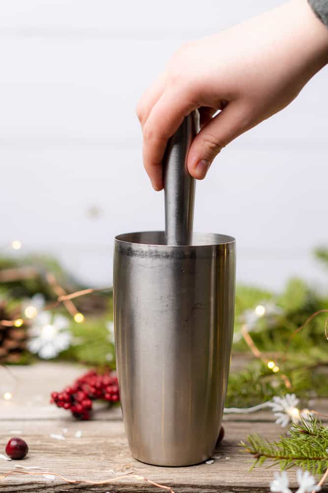 muddling christmas mojito in a cocktail shaker