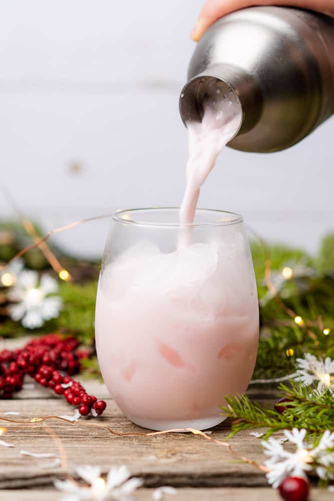 straining a pink cocktail into a glass