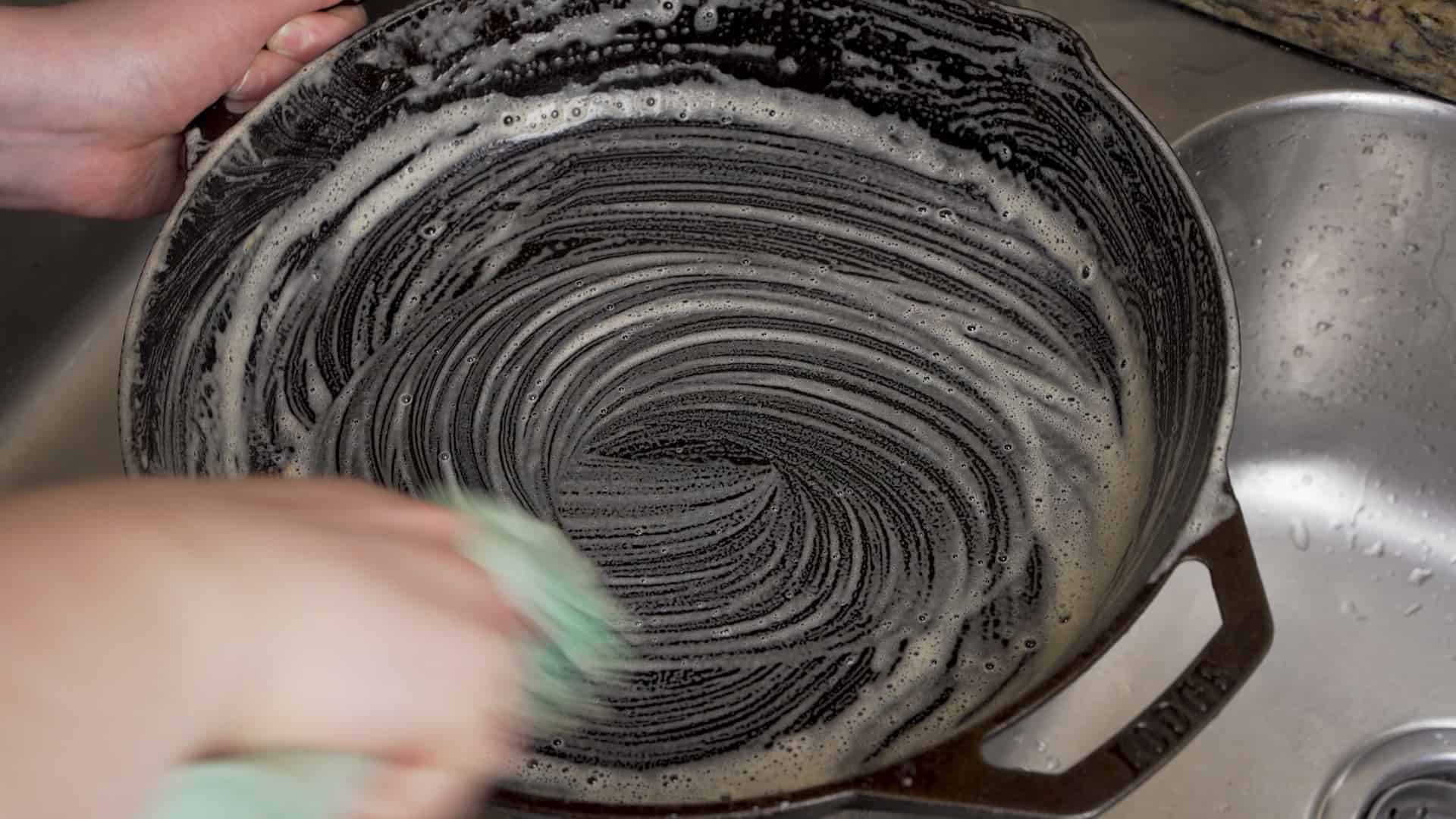 scrubbing soap into a cast iron skillet