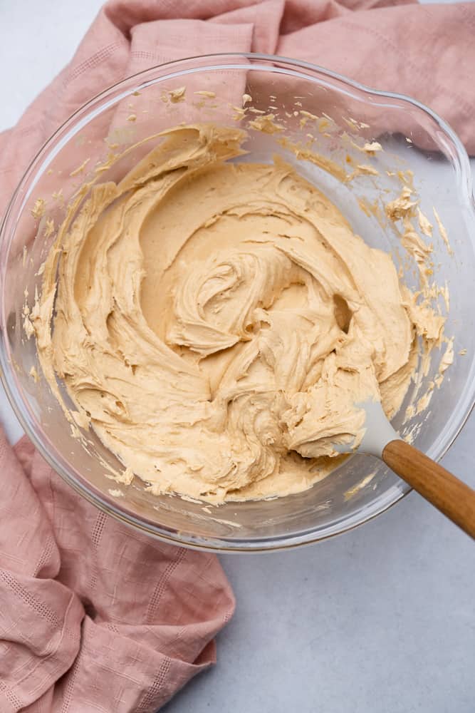 peanut butter cream cheese frosting coming together in a bowl with a rubber spatula