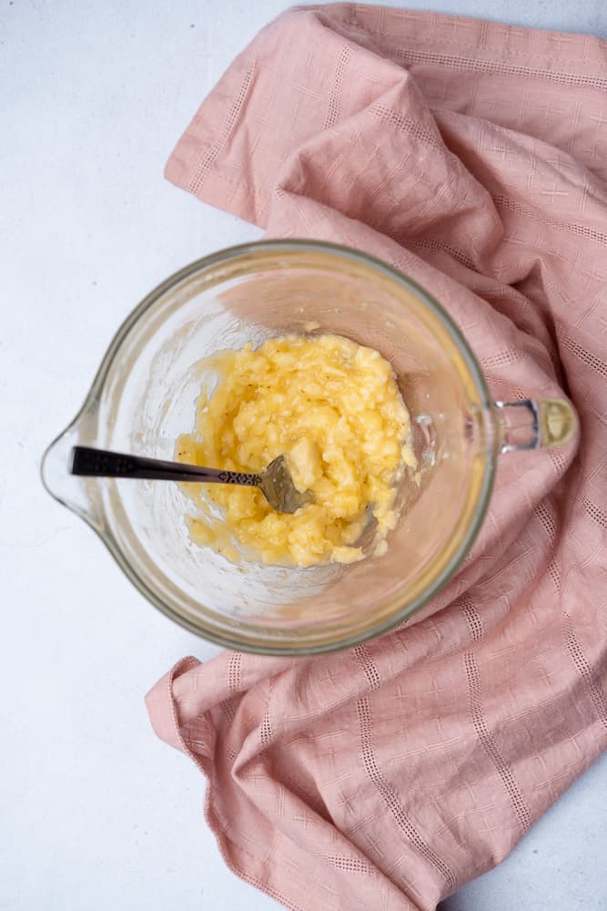mashed bananas in a glass bowl with a fork