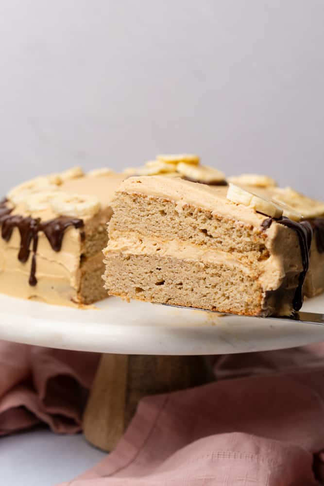 two layer slice of a banana dream cake with peanut butter frosting and a chocolate ganache