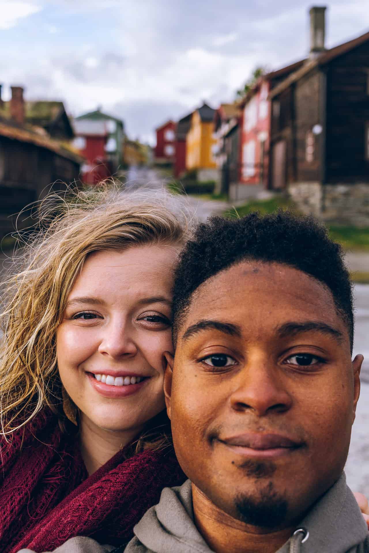 man and woman smiling together with a backdrop of a lovely and colorful norwegian city