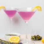 two pretty lavender martinis in glasses with slices of lemon