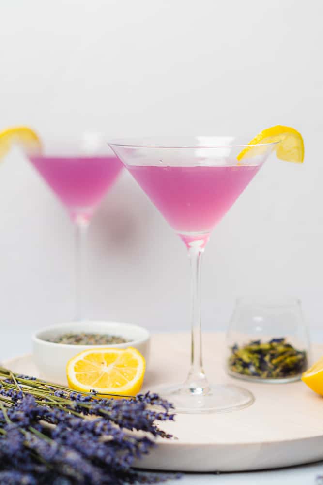 two pretty lavender martinis in glasses with slices of lemon