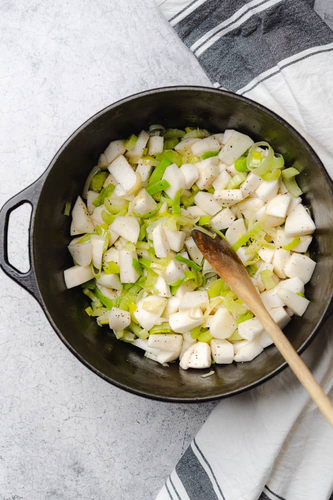 turnips celery and leeks in a cast iron dutch oven for potato leek and kale soip